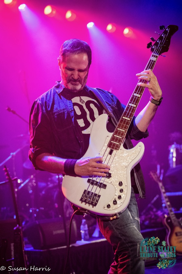 Bassist with a white bass under pink lights